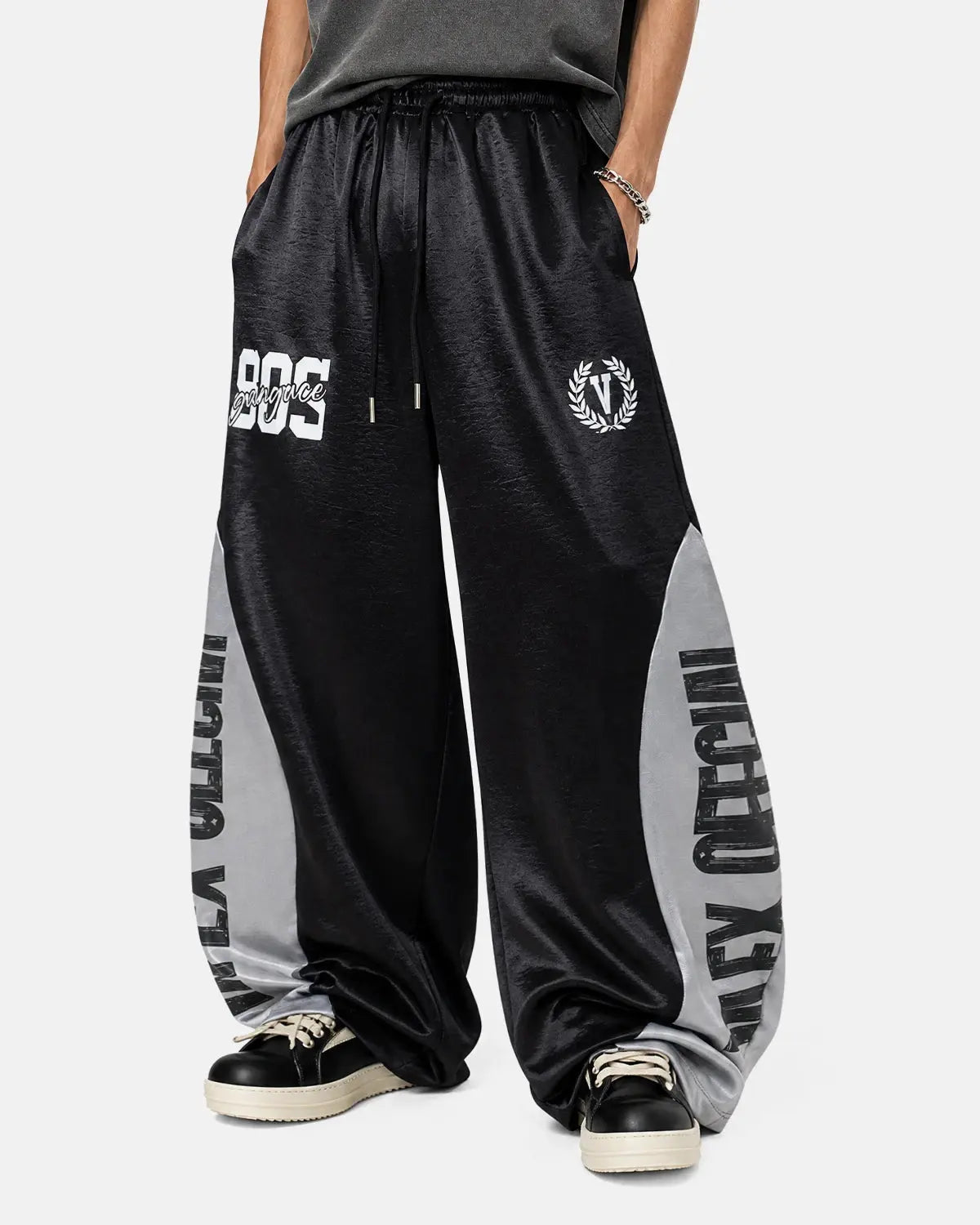 Model wearing glossy black contrast barrel sweatpants by INFLATION, featuring a relaxed fit and stylish design.