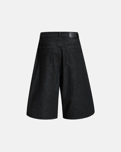 Asymmetric button raw denim jorts by Flation, casual streetwear pants with distressed finish and raw hem, front view.