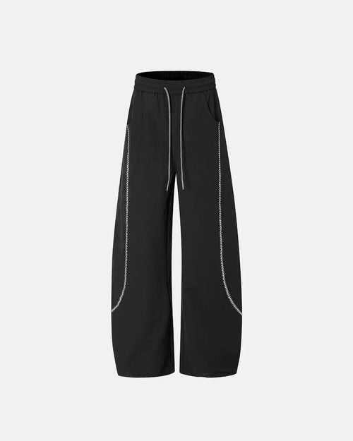 INFLATION AirFlow Contrast Embroidered Track Pants showing black fabric with colorful embroidered details and tapered fit.