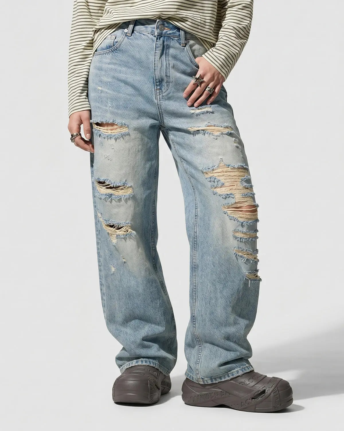 Distressed ripped straight-leg jeans by INFLATION streetwear, showing faded denim with frayed holes and a relaxed fit.