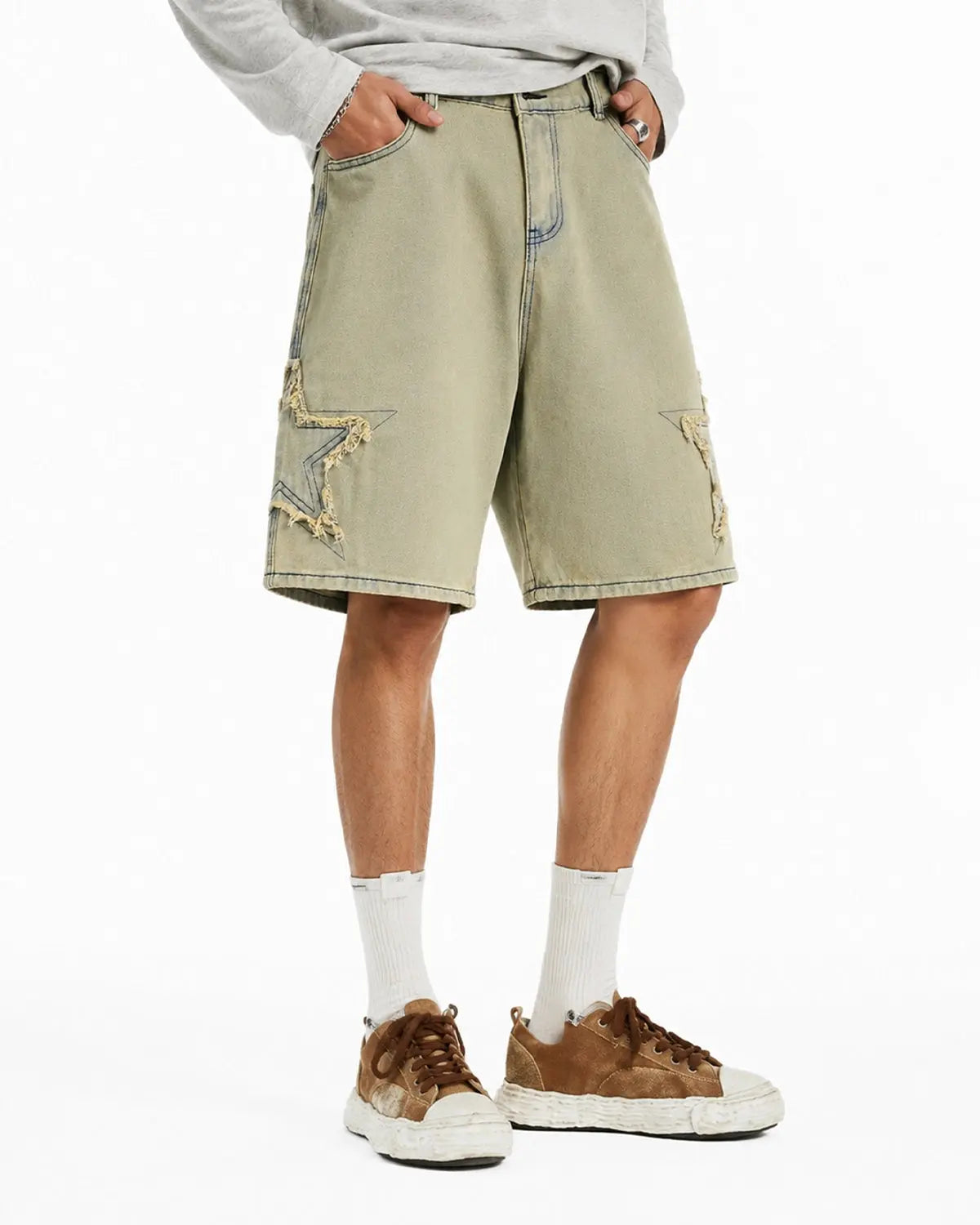 Distressed baggy jorts with star patch details from INFLATION's Streetwear collection, shown on a model.