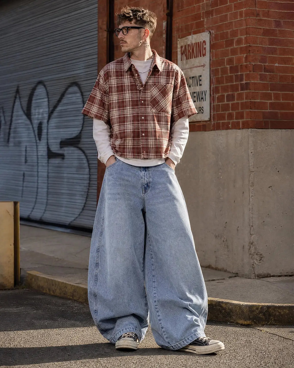 Flation acid washed distressed barrel jeans, streetwear style, showing faded denim with rips and frayed edges.