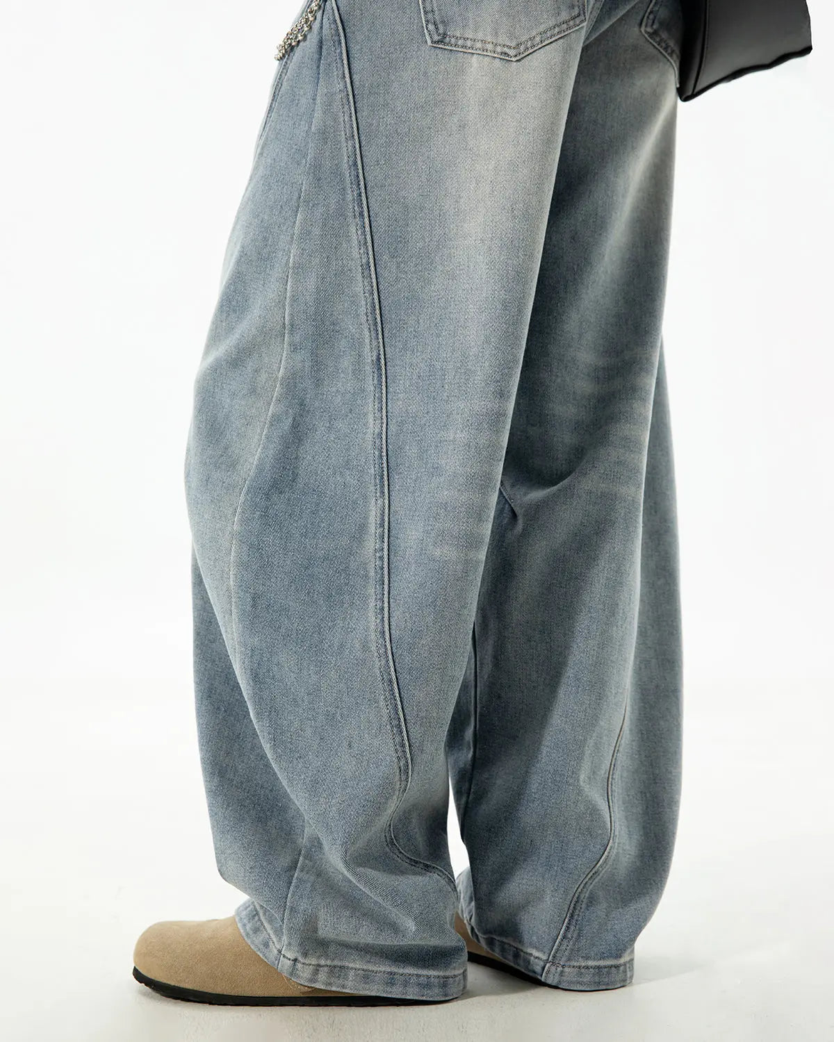 Curved seam deconstructed barrel jeans by Inflation Streetwear with distressed detailing and relaxed fit, shown on a hanger.