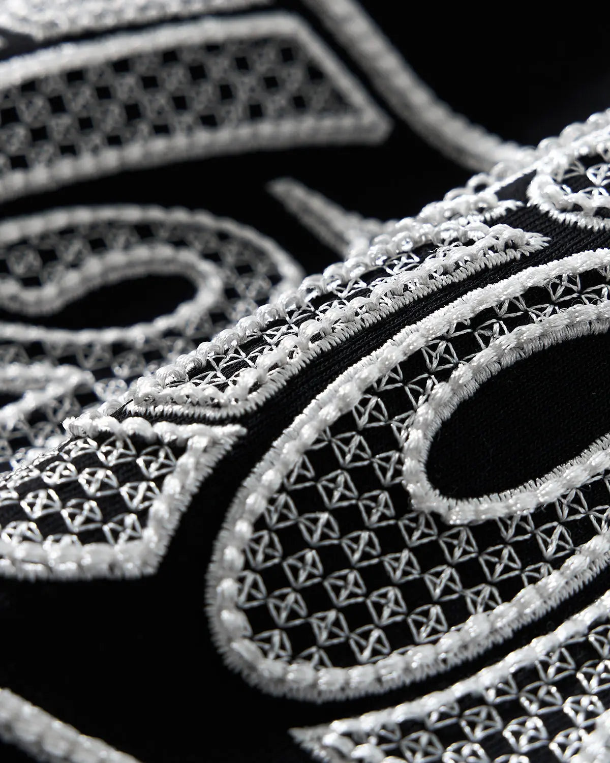 Hollow embroidered graphic T-shirt by INFLATION featuring bold design on white cotton fabric, streetwear style.