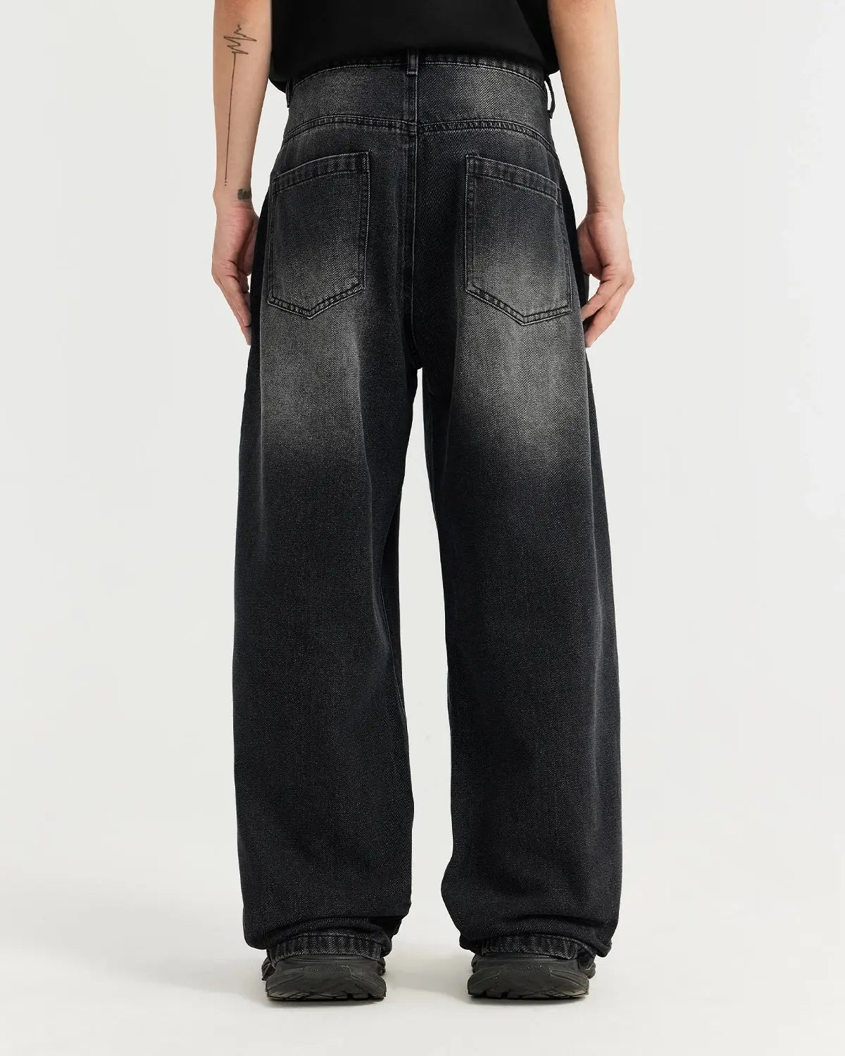 Black washed baggy jeans from Flation Streetwear, showing relaxed fit and distressed denim texture.