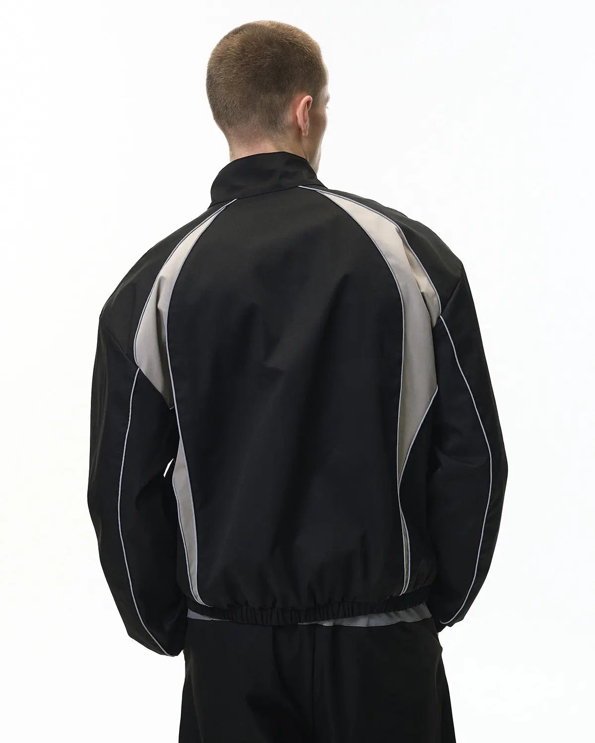 Flation reflective windbreaker track jacket with hood, lightweight streetwear style, featuring shiny, reflective fabric and front zipper.