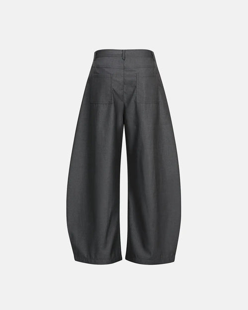 Asymmetric pleated barrel-leg suit pants by Flation, showing the unique pleats and tailored fit in a neutral color.