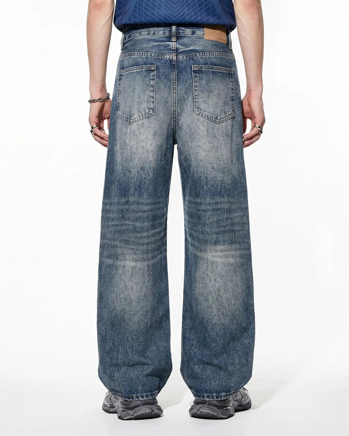 Distressed baggy jeans from INFLATION's Whisker Wash collection, featuring a relaxed fit and faded, worn-in denim style.