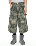 Washed camo cargo longline shorts by INFLATION, featuring multiple pockets and a relaxed fit, displayed on a mannequin.