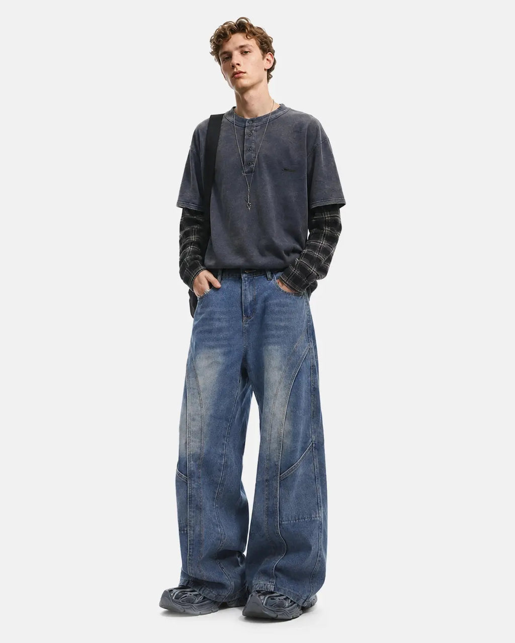 Deconstructed baggy straight-leg jeans by INFLATION featuring distressed details and relaxed fit, shown on a hanger.