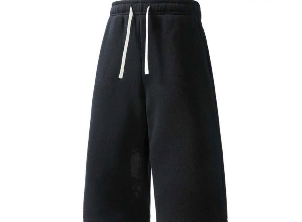 Flation Trending Long Jogger Shorts in black, featuring an elastic waistband and relaxed fit, displayed on a hanger.