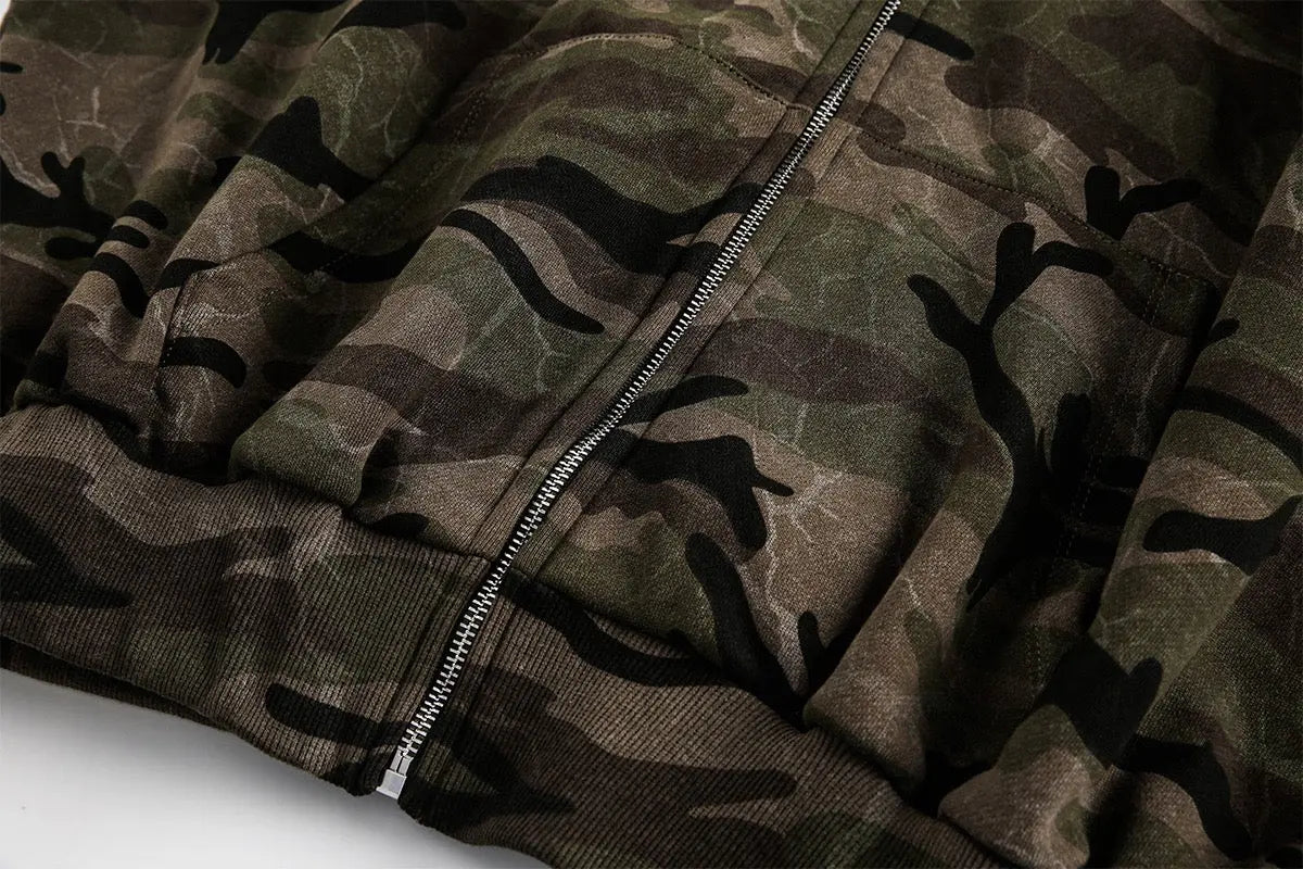 Camouflage zip-up jacket by Flation Streetwear with front pockets and adjustable hood, displayed on a hanger.