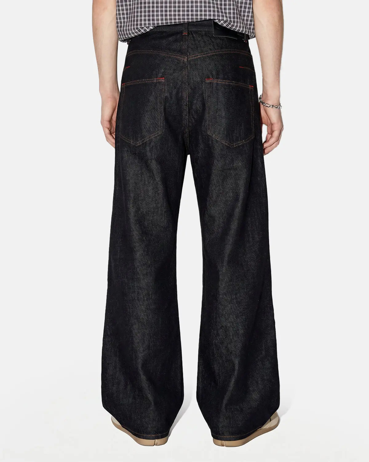 Black Flation asymmetric buckle raw baggy jeans with distressed detailing, streetwear style, relaxed fit, and unique asymmetric design.