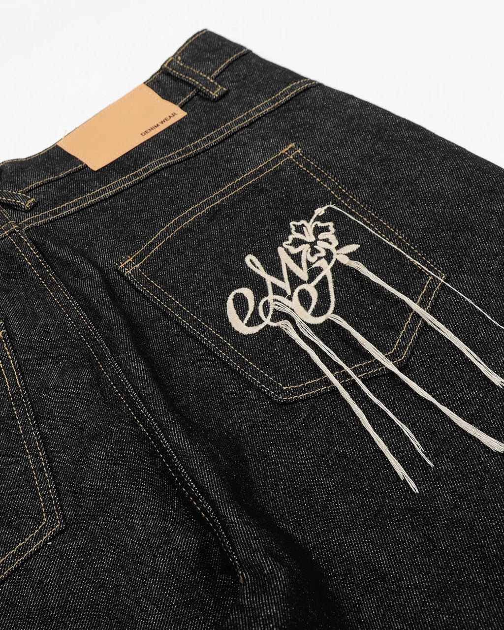 Black deconstructed raw denim jorts by Flation, streetwear-style pants with frayed edges and distressed details.