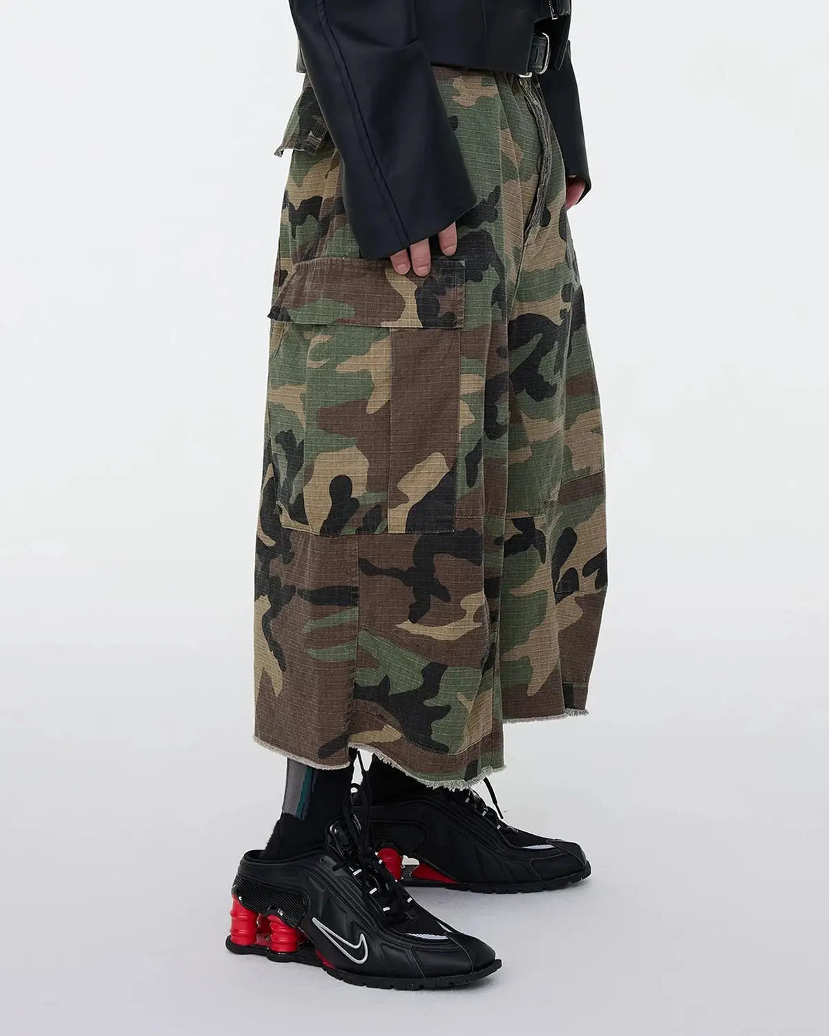 Oversized camo cargo longline shorts by Flation Streetwear featuring green camouflage pattern and multiple utility pockets.