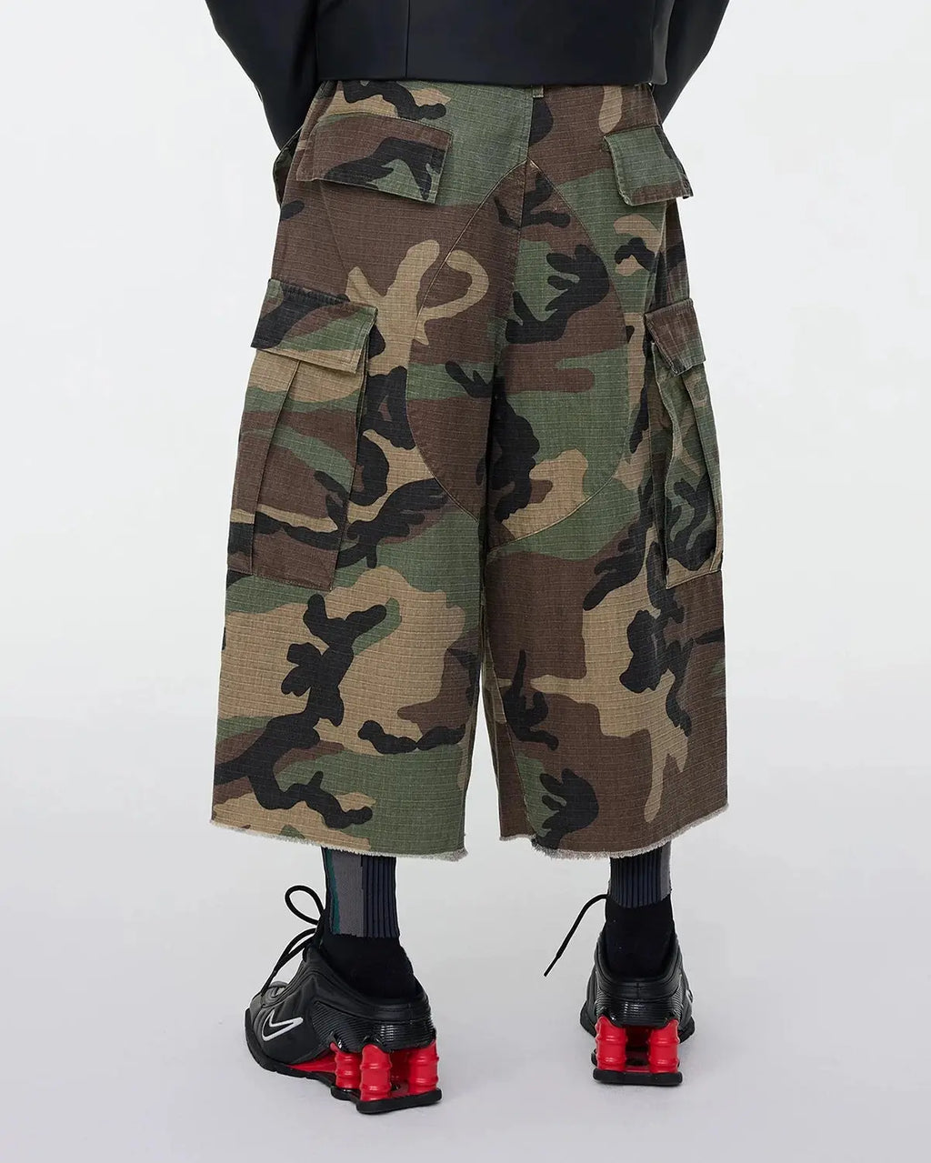 Oversized camo cargo longline shorts by Flation Streetwear featuring multiple pockets and a relaxed fit in green camouflage print.