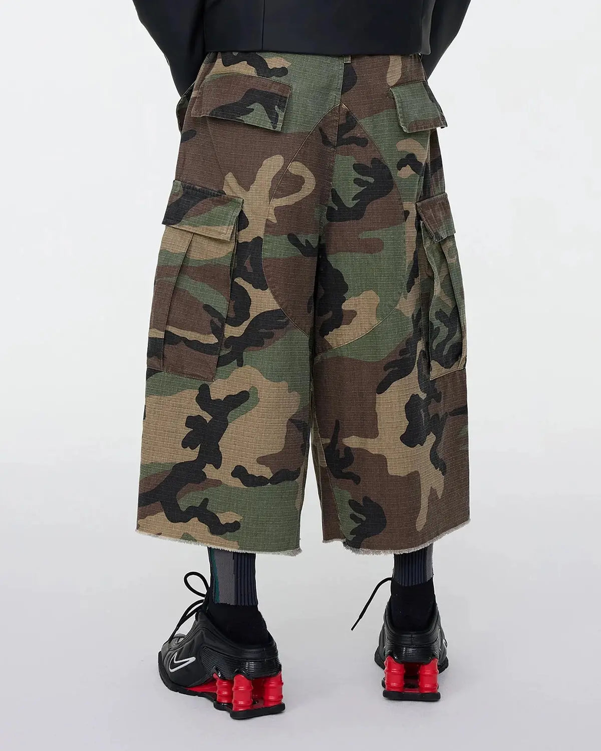Oversized camo cargo longline shorts by Flation Streetwear featuring multiple pockets and a relaxed fit in green camouflage print.